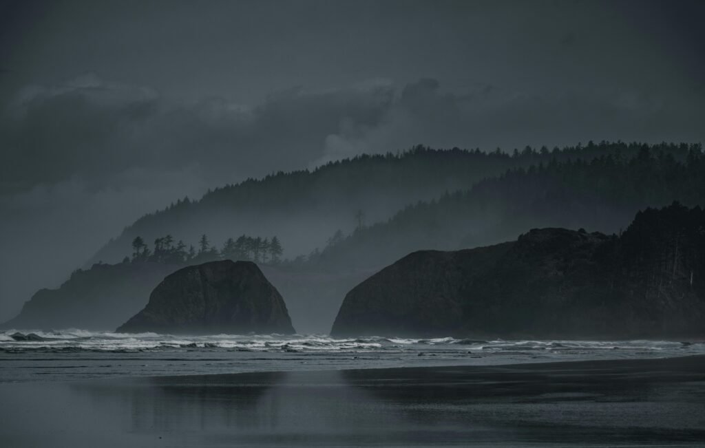 A dramatic, misty coast with rugged cliffs and dark sky, evoking a sense of mystery and solitude.