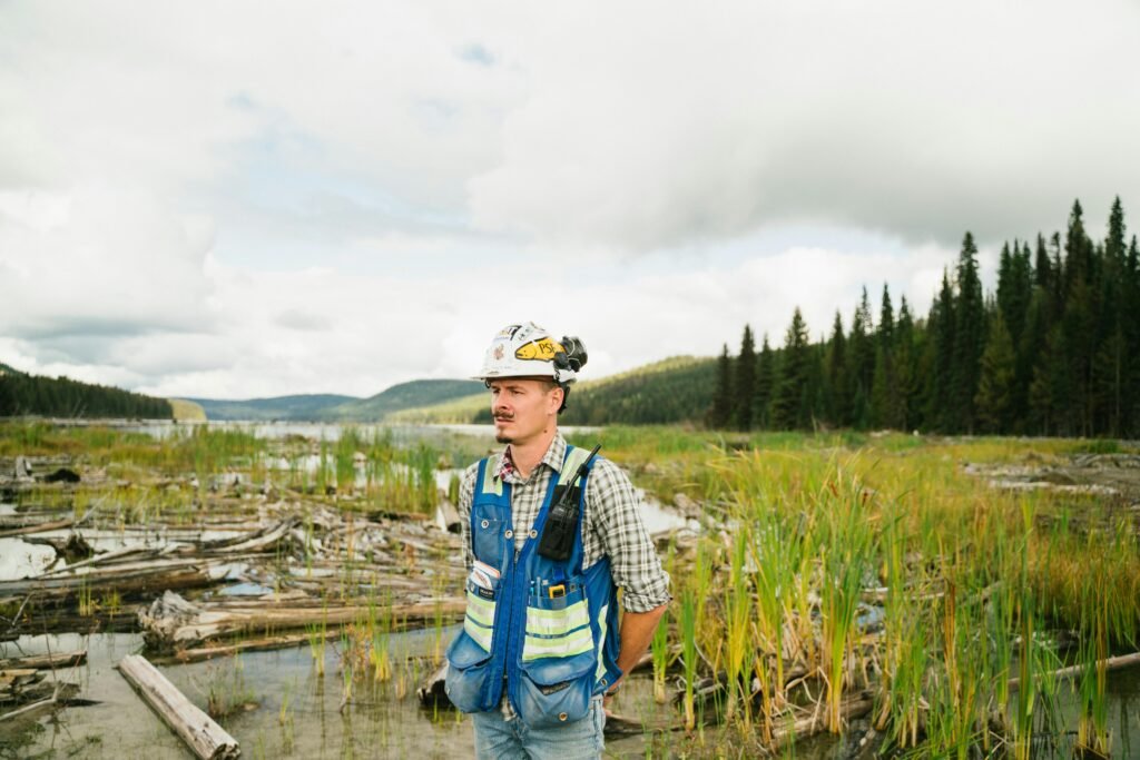 Environmental engineer wearing safety gear in BC wilderness, exploring nature and environmental impact.