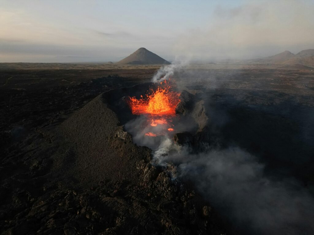 An erupting volcano in Iceland captured from above, showcasing vibrant lava and smoke.