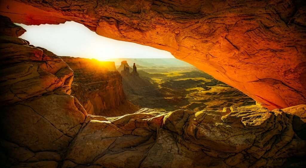 Captivating view of sunrise through Mesa Arch, showcasing breathtaking rock formations and desert landscape.