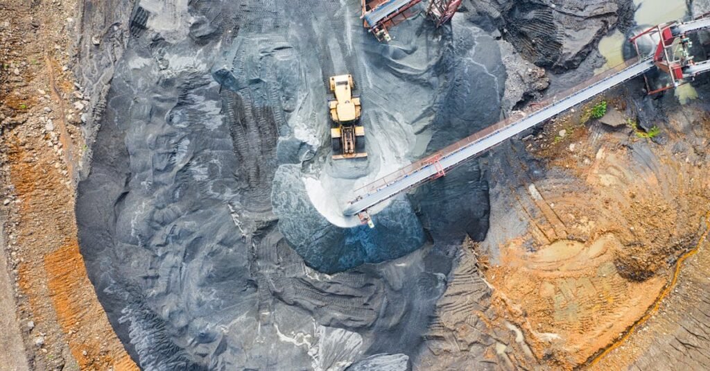 Aerial view of a large industrial mining site with heavy machinery and conveyor belts in operation.