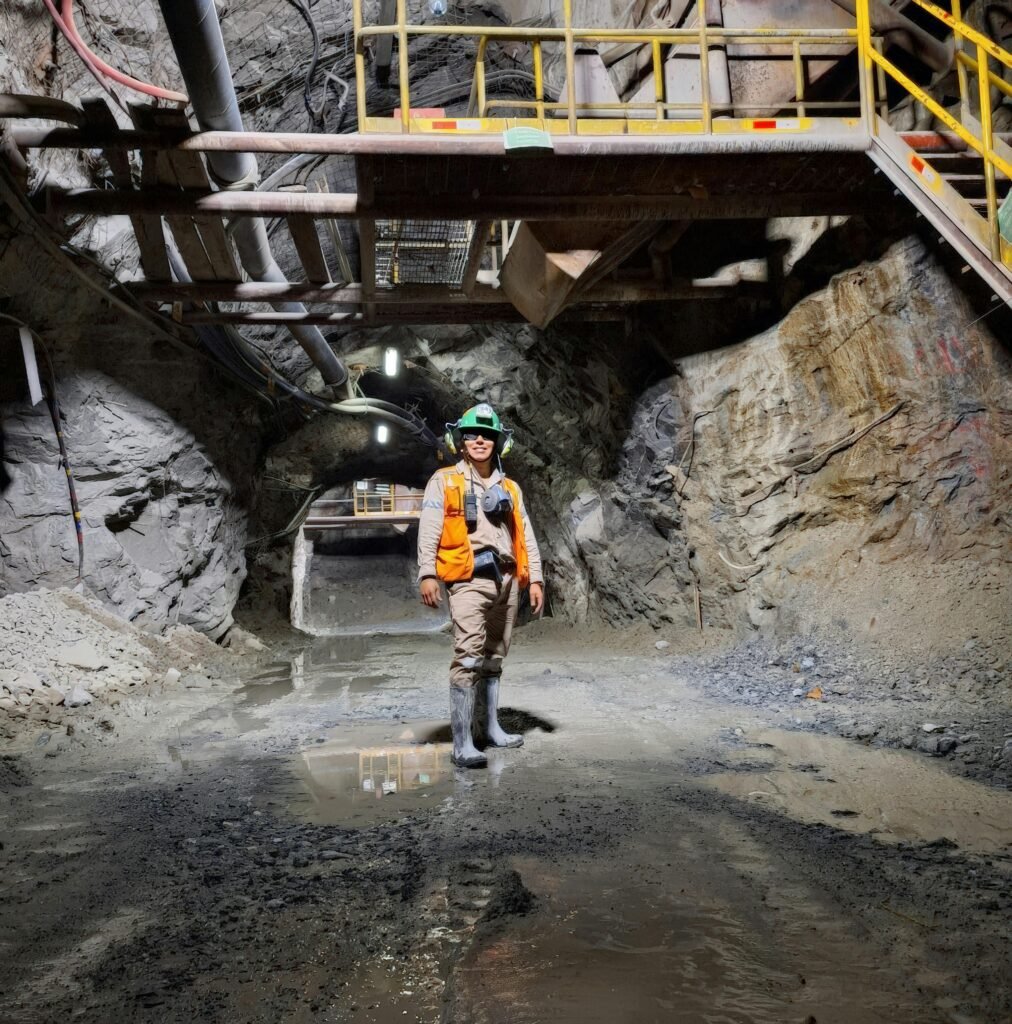 Engineer standing in an illuminated underground mine tunnel, showcasing mining safety gear and modern infrastructure.