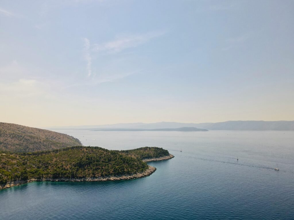 Serene aerial view of the Croatian coastline near Nerežišća with tranquil sea and lush greenery at sunset.